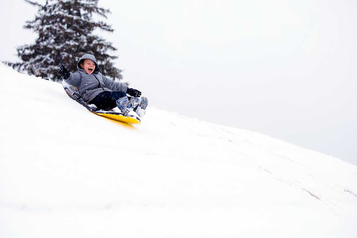 A child goes down a sledding hill on a winter holiday.